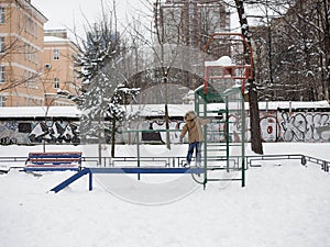 Orphan child alone in the playground in winter, graffiti background