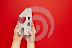 Orphanage concept. Nursing home care. House with hearts in hands on a red background. Real estate insurance