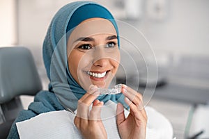 Orthodontics Concept. Smiling Muslim Woman In Hijab Holding Invisalign Or Invisible Braces