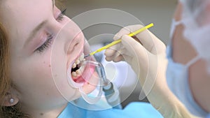 Orthodontist covering special gel on woman teeth in dentistry using brush.