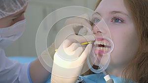 Orthodontist covering special gel on woman teeth in dentistry using brush.