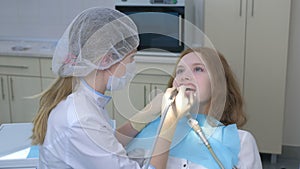 Orthodontist covering special gel on woman teeth and drying it in dentistry.