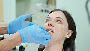 Orthodontist doctor checks the closing of the woman teeth using carbon paper.