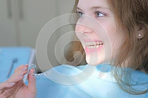 Orthodontist doctor installed silicone transparent braces on girl`s teeth.