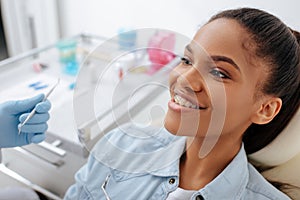 Orthodontist in holding dental instruments near happy african american patient