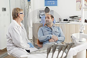 Orthodontist senior doctor explaining oral hygiene to man patient