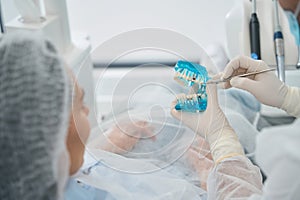 Orthodontist shows a model with dental implants to a patient