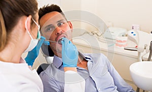 Orthodontist in uniform is examinating adult patiant on the chair