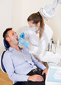 Orthodontist in uniform is examinating male patient