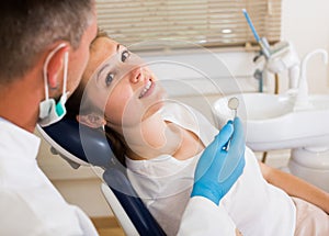 Orthodontist in uniform is taking visional inspection of a young female