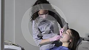 The orthodontist using dental impression tray on woman teeth.
