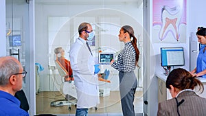 Orthodontist using tablet explaining dental x ray to patient