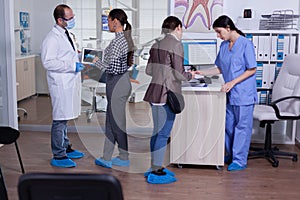 Orthodontist using tablet explaining dental x ray to patient standing in waiting area