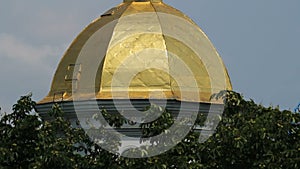 Orthodox Christian church dome topped with golden cross, cloudy sky background