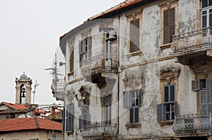 Orthodox Church Bell Tower and Abandoned Greek Home with Shutter and Balcony in Hatay, Turkey photo