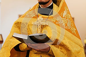 Orthodox Church. Christianity. Priest hands holding Holy Bible book in traditional Orthodox Church background on wedding day,