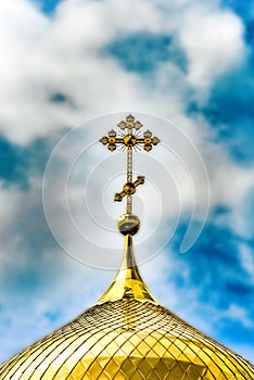 Orthodox Church, golden domes with crosses close-up against a blue cloudy sky, HDR photo