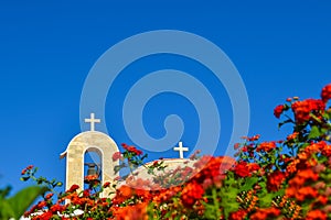 Orthodox church with a tiled roof and a bell. Red roses in the foreground. Cyprus. Ayianapa. Church of St. Epiphany. photo