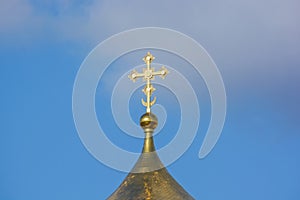 Orthodox cross at church rooftop against blue sky