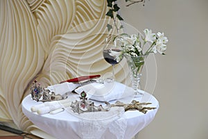 Orthodox cross, crowns for the bride and groom, the Bible, wedding rings on the pillow, candles, a glass of wine, orchids in a vas