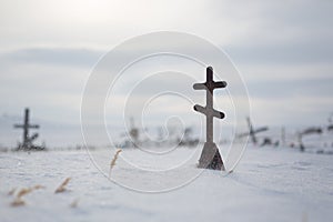 Orthodox cross on a snow-covered grave in the cemetery of an abandoned Arctic village