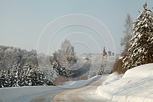 Orthodox monastery in the heart of the winter forest with snow covered road and fir trees