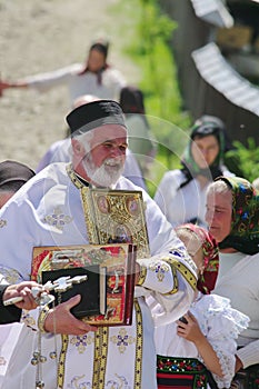 Orthodox priest and people in traditional national costumes - a village in Maramures, Romania