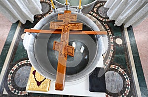 An Orthodox wooden cross, prepared for the consecration of water, lies on a bowl. photo