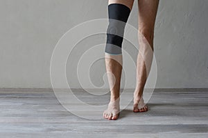 Orthopedic Anatomic Orthosis. Braces for knee fixation, injuries and pain. Knee Support Brace on leg at home on gray wall