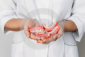 An orthopedic dentist holds dentures in his hands. Dentures in the hands of a doctor. Orthopedic dentistry. False teeth. Dentistry