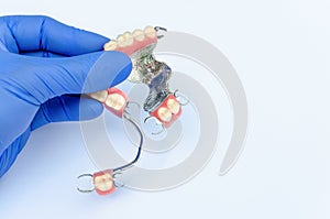 Orthopedic dentistry. prosthetics concept with removable dentures. a dentistÃ¢â¬â¢s hand in a glove holds a set of clasp prostheses photo