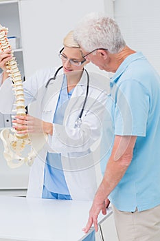 Orthopedic doctor and senior patient discussing over anatomical spine