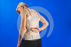 Orthopedic lumbar corset on the human body, back pain and wound care, blue background, healthcare