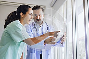 orthopedic surgeon examines an x-ray film of a patient's knee joint and recommend symptoms to patients