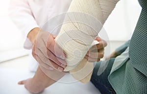 Orthopedist applying bandage onto patient`s hand in clinic