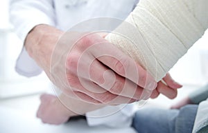 Orthopedist applying bandage onto patient`s hand in clinic