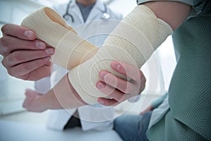 Orthopedist applying bandage onto patient`s hand in clinic