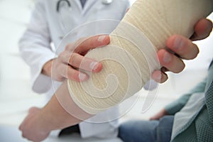 Orthopedist applying bandage onto patient`s hand in clinic