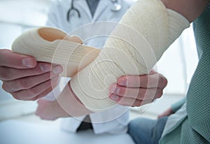 Orthopedist applying bandage onto patient`s hand in clinic