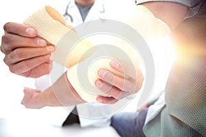 Orthopedist applying bandage onto patient`s hand in clinic