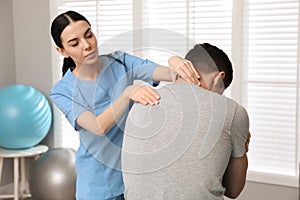 Orthopedist examining man`s neck in clinic. Scoliosis treatment