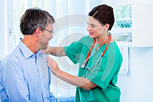 Orthopedist examining shoulder of patient in surgery