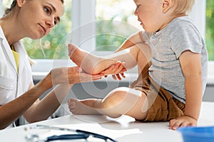 Orthopedist podiatrist checking child patient feet condition in clinic office