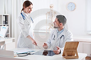 Orthopedists examining X-ray picture at desk in clinic