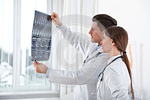 Orthopedists examining X-ray picture near window