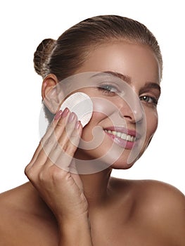 Ortrait of a girl with pure and healthy glowing skin without makeup, who is doing daily cleansing procedures using a cotton pad