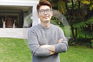 ortrait of happy asian man wearing glasses smiling in garden outside family home