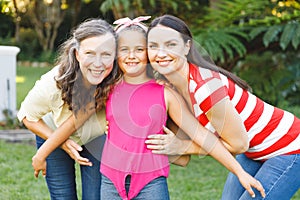 ortrait of smiling caucasian grandmother with adult daughter and granddaughter in garden