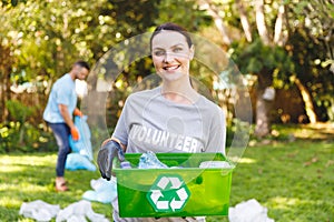 ortrait of smiling caucasian woman holding recycling box, cleaning up countryside with husband