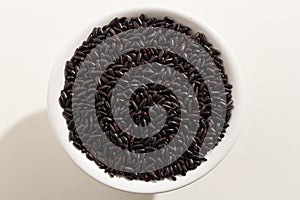 Black Rice seed. Top view of grains in a bowl. White background.